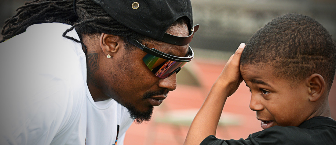 Marshawn Lynch talks with a young boy attending his Fam 1st football camp