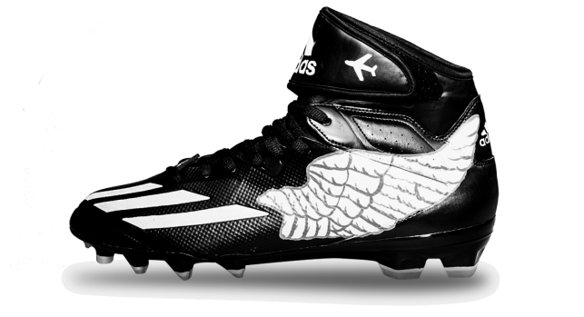 Left side of Graham's black cleat, with white wing design with an airplane icon above, near back, and 3 slashes near front of shoe